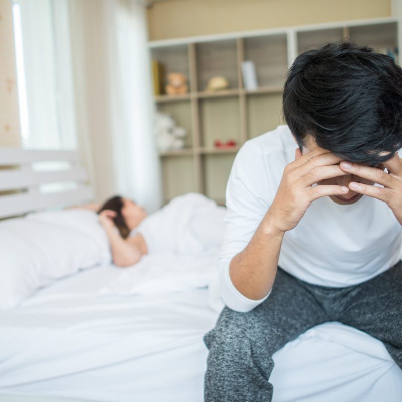 Upset man having problem sitting on the bed after arguing with his girlfriend